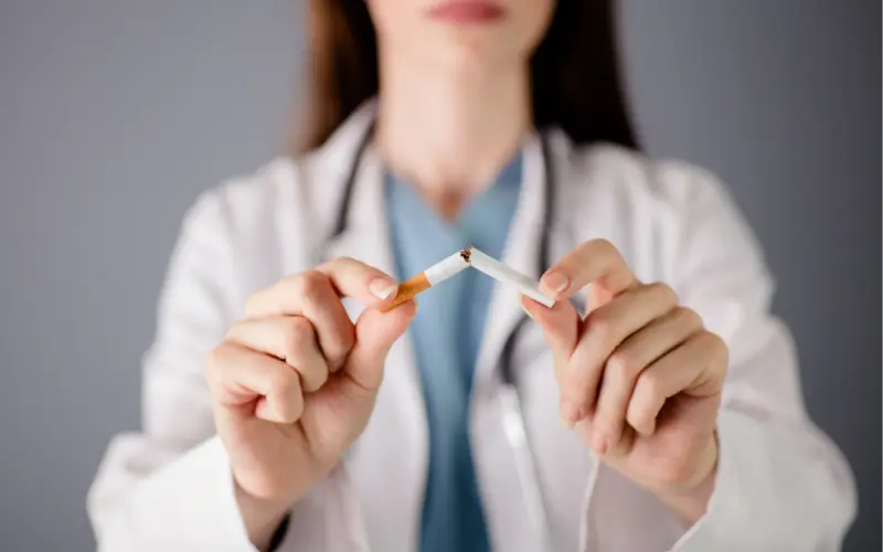 Une soignante casse une cigarette en deux entre ses mains.